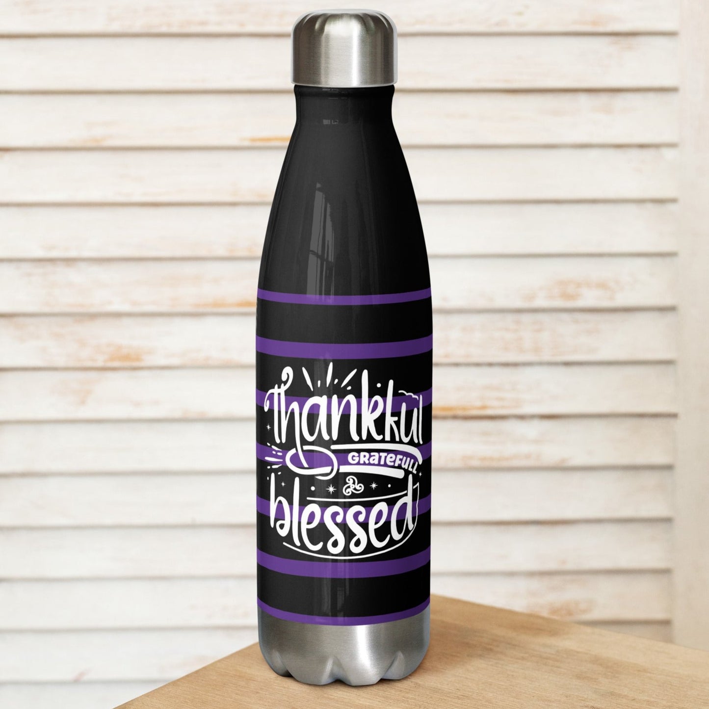 Front view of a black stainless steel water bottle with purple and white lines and white text saying 'Thankful and blessed'