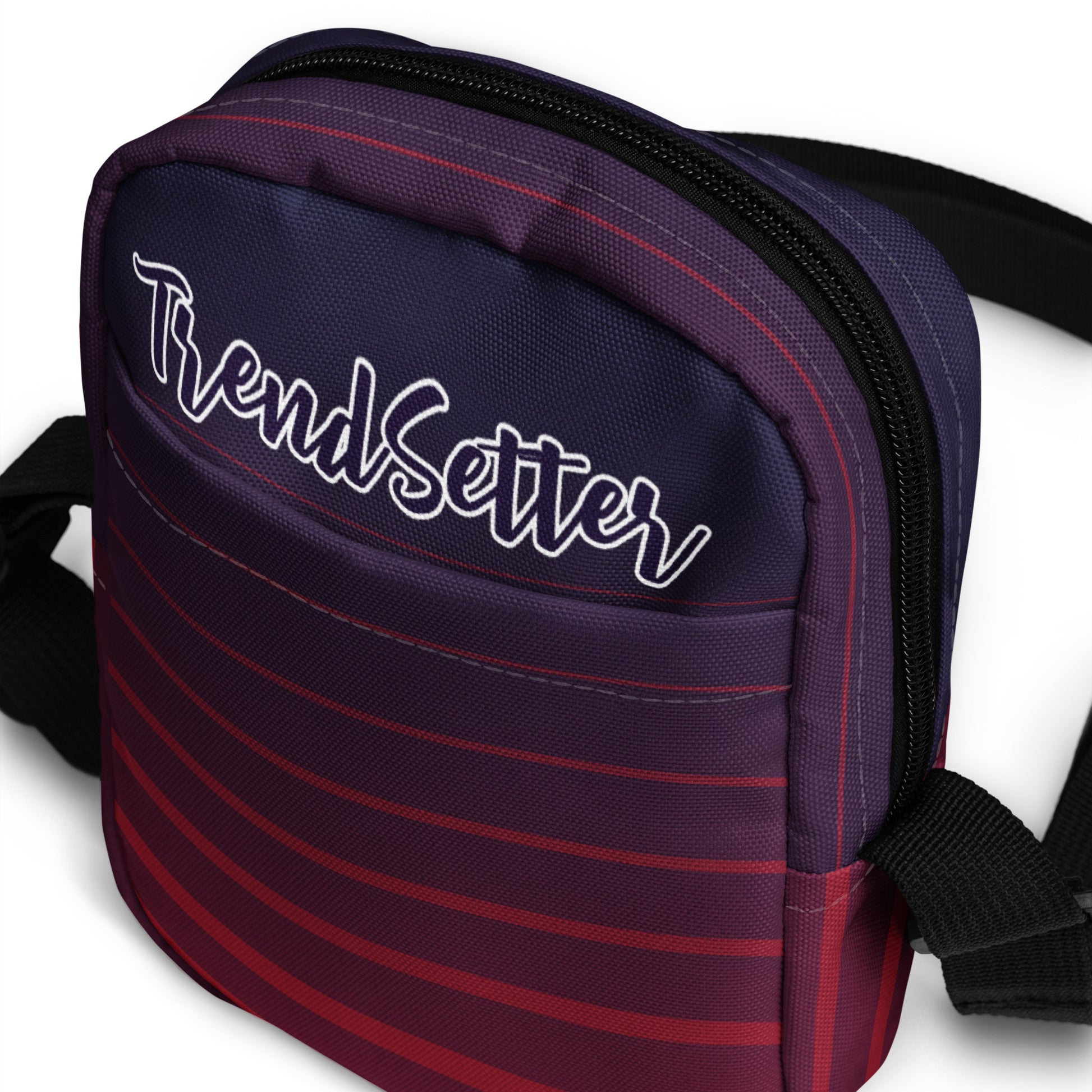 Front slanted view of TrendSetter Utility Crossbody Bag with red and blue stripped design and with TrendSetter logo