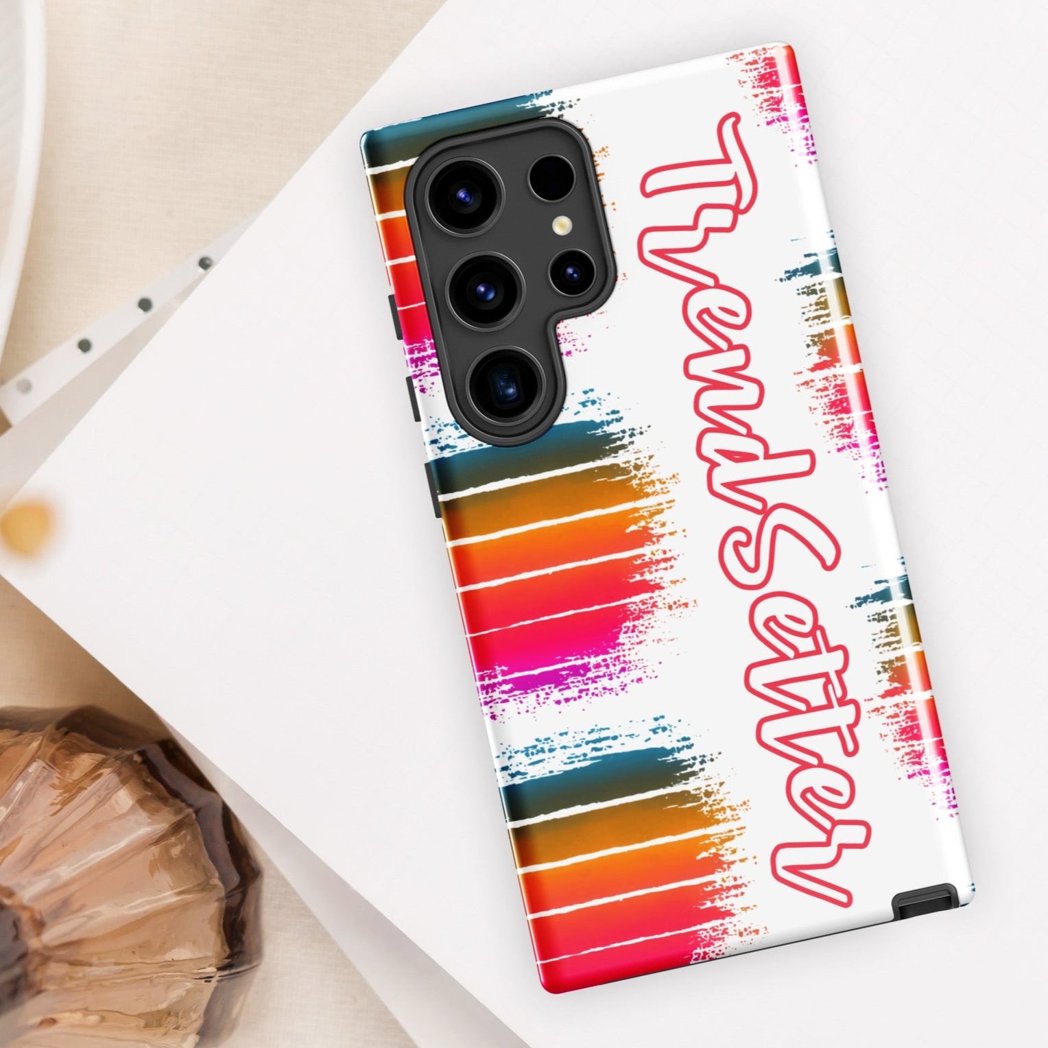 Front of Samsung cover with white background with 3 color striped balls on left side and partial view of colored striped balls on right side. Text saying "Trendsetter" runs down from top to bottom.