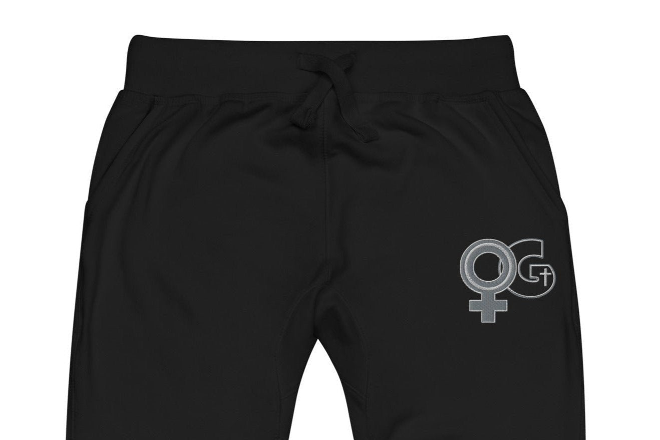 Front of black sweatpants with embroidered symbol for woman of God on front, left thigh