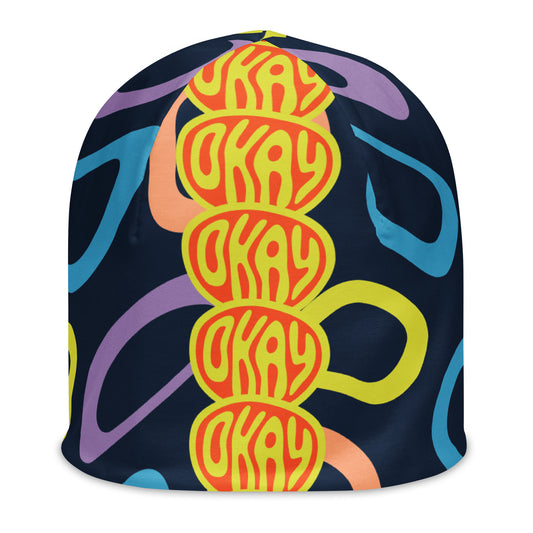 Front of multi-colored and black print youth beanie with red and yellow icon saying 'okay'