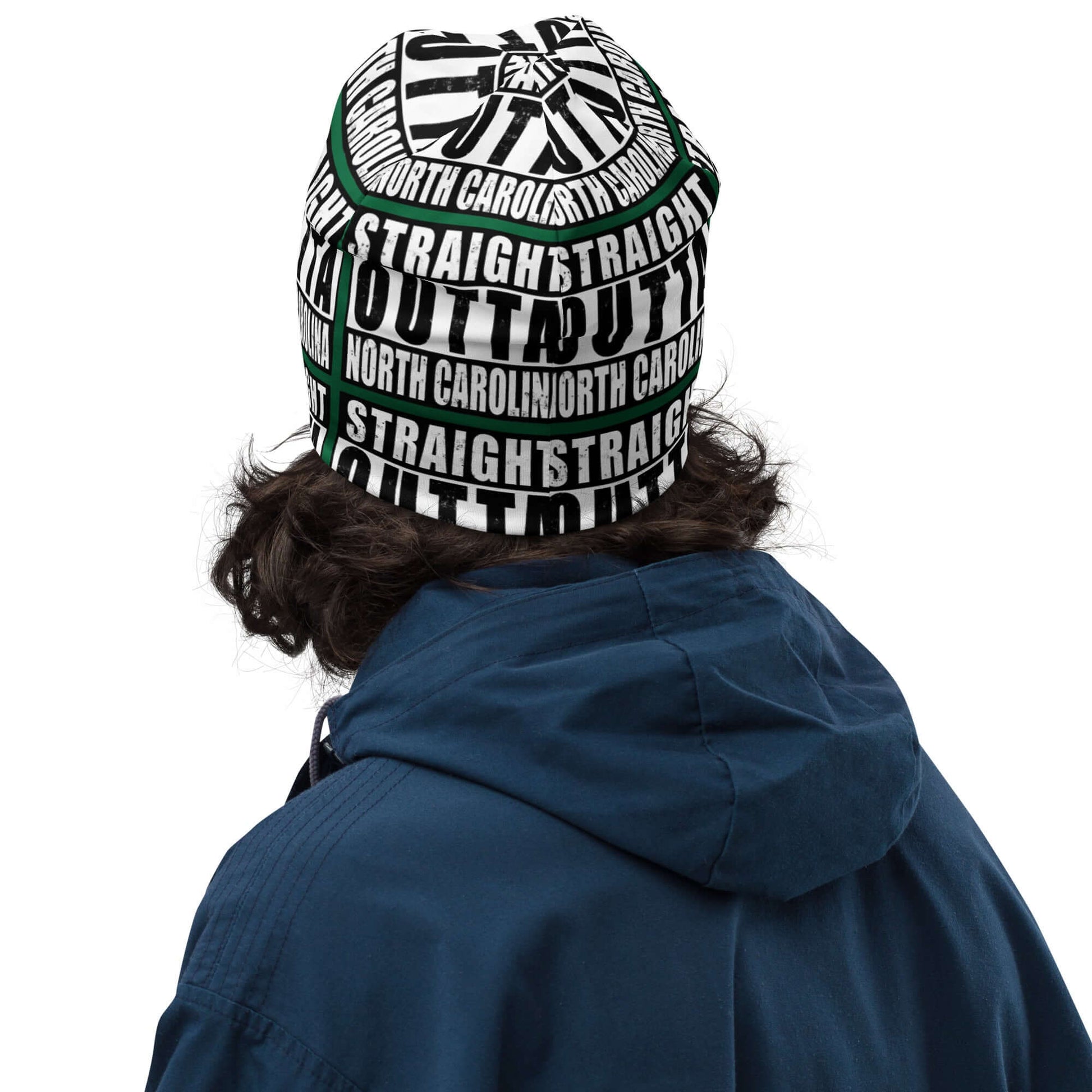 Man wearing unisex beanie w/all-over print of the Straight Outta North Carolina image on a green background, back view