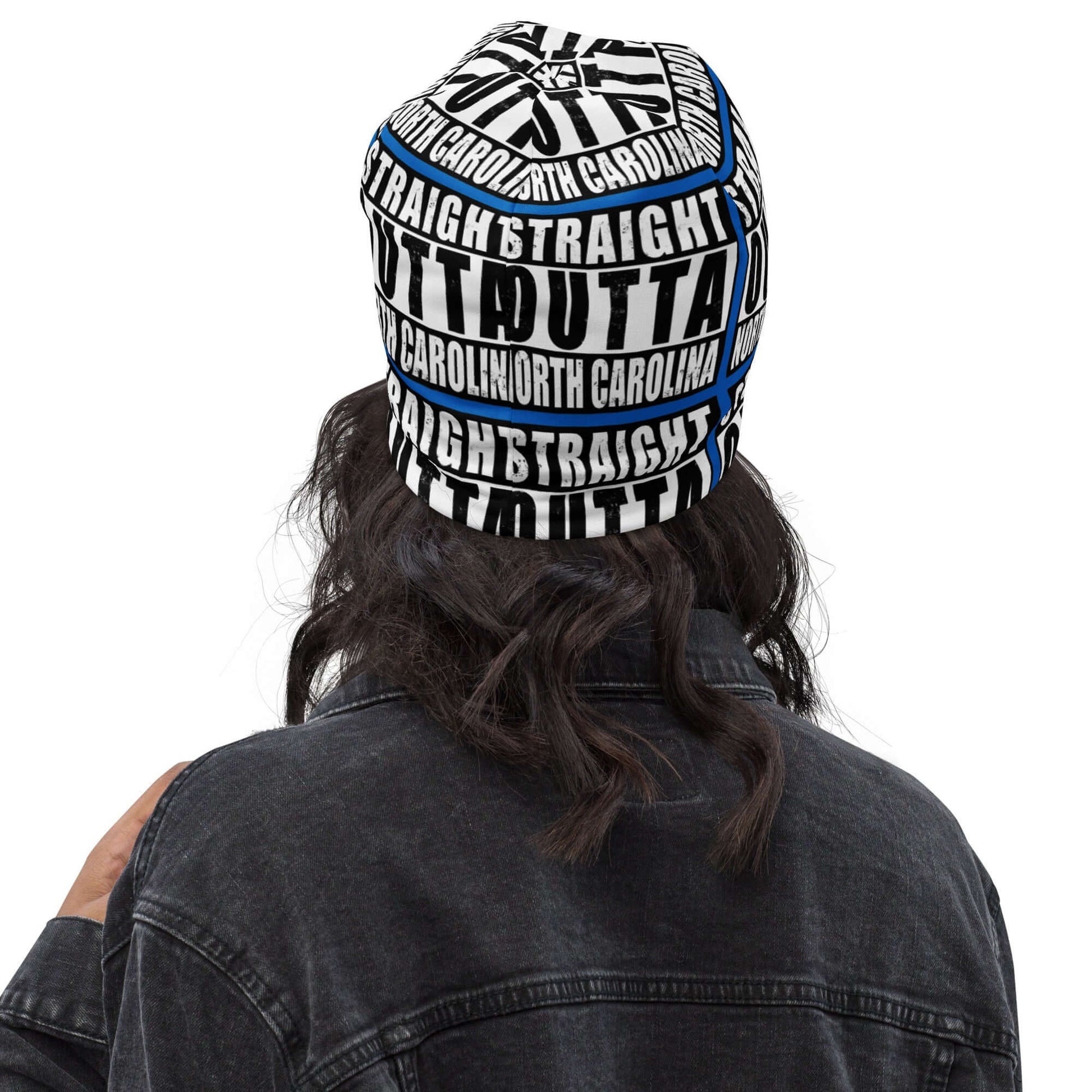 Woman wearing unisex beanie w/all-over print of the Straight Outta North Carolina image on a blue background, back view