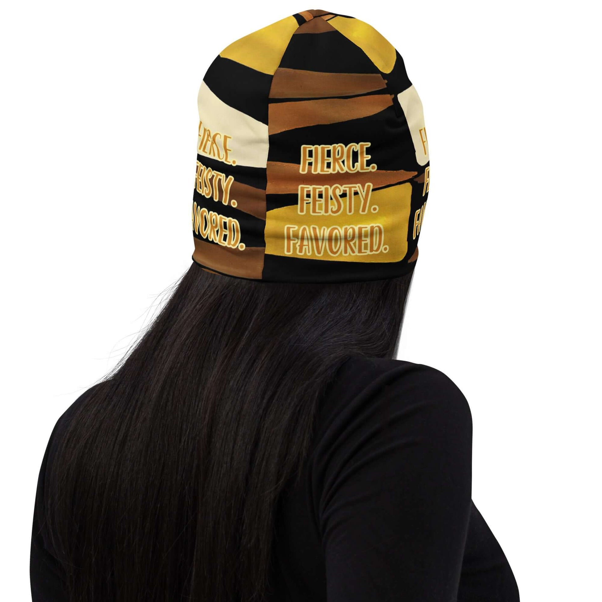 Head shot of woman wearing the Fierce. Feisty. Favored. black, brown, beige and gold print beanie, back view