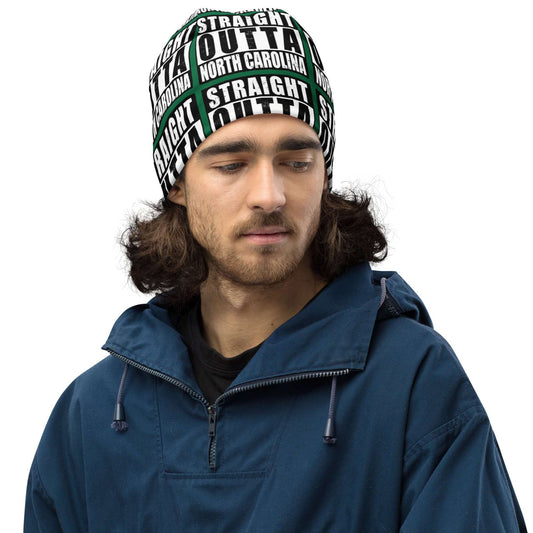 Man wearing unisex beanie w/all-over print of the Straight Outta North Carolina image on a green background, front view