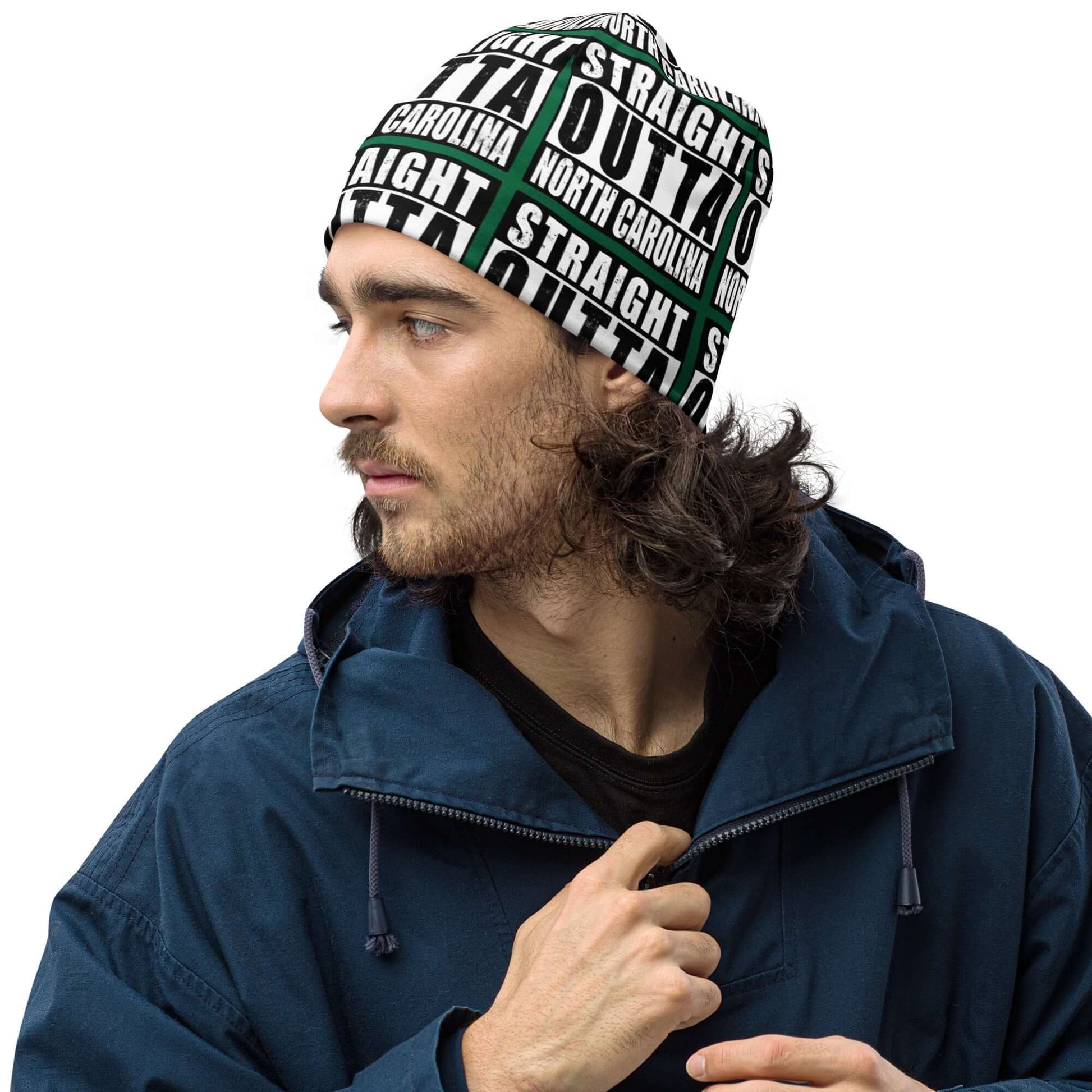 Man wearing unisex beanie w/all-over print of the Straight Outta North Carolina image on a green background, front left view